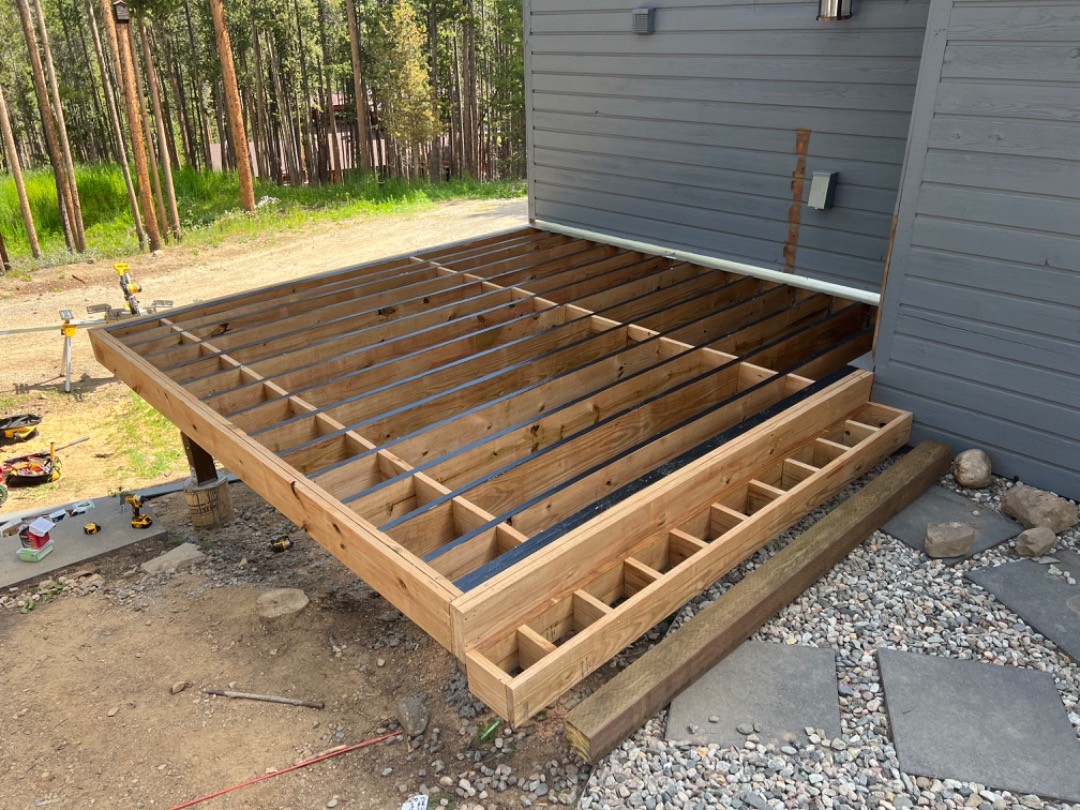 Framing of an attached deck job we completed showing framing, footings, pillars, and stairs