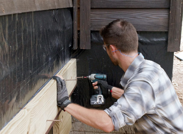 Technician attaching a deck ledger to a house