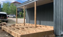 Finished framework for ground-level wood deck beside blue house