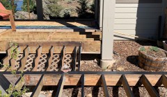 Framework for wooden walkway and staircase to wood deck behind beige home