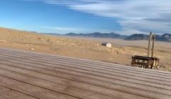 Walnut wood porch without railing overlooking grassland and distant mountains