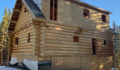 Partially constructed log cabin on snowy day