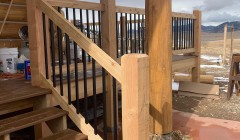 Partially constructed wooden patio beside log cabin overlooking mountains