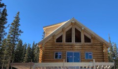 Partially constructed log cabin and wooden gazebo above front patio area