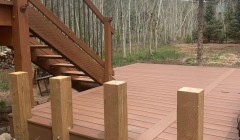 Wooden deck with four vertical planks for future railing and wooden stairs to upper level