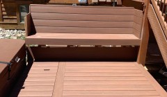 Wooden bench beside covered hot tub and wood deck