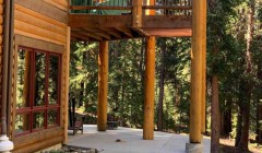 Large wood cabin with second-story wood deck and adjacent wooden support beams