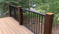 Wooden deck with metal railings and walnut support beams overlooking forest
