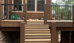 Finished pine wood staircase with four walnut support beams leading to large wooden deck