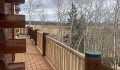 Log cabin with composite wood deck and pine wood railings with dark oak support beams