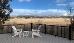 Composite wood deck and white patio furniture surrounded by black metal railings