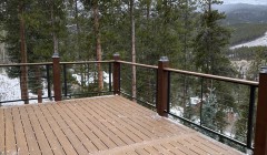 Composite wood deck with cable railings overlooking forest and mountains