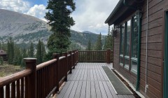 Cabin with walnut siding beside matching deck with surrounding wood railing