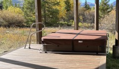 Covered hot-tub with safety railing built into covered wooden porch