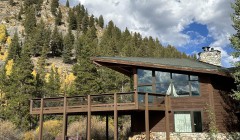 Custom log cabin with large wooden deck and asymmetrical roof