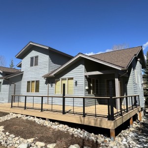 Pine wood deck with cable railings outside blue house