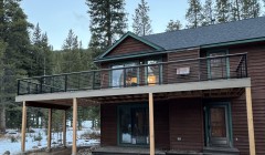 Second-story outdoor deck with metal railing outside walnut cabin