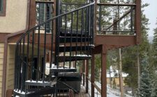 Black outdoor spiral staircase to second-story walnut wood deck