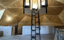 Black metal ladder-style staircase to lighthouse with custom pine ceiling