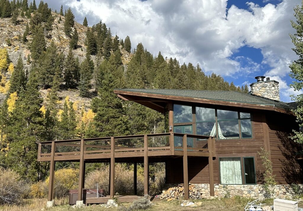 Custom log cabin with large wooden deck and asymmetrical roof